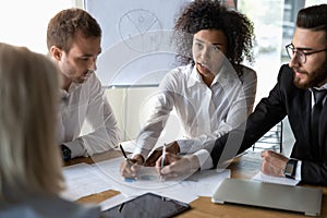 Multiethnic colleagues discussing financial paperwork at briefing