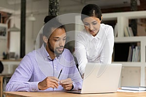 Multiethnic colleagues work together on laptop in office