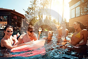 Multiethnic company of friends in swimming pool. Company of young people spend weekend in pool.