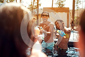 Multiethnic company of friends in swimming pool at summertime. Swimming pool party.