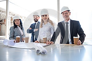 Multiethnic contractors in formal wear working with blueprints at construction area photo