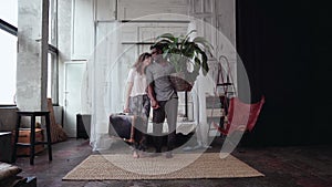 Multiethnic couple gather in travel. Woman holds suitcase, man holds plant. Boy and girl kisses and goes away.