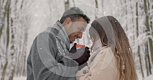 Multiethnic couple hugging each other in winter forest