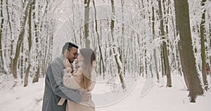 Multiethnic couple hugging each other in winter forest