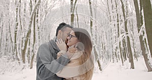 Multiethnic couple hugging each other in winter forest