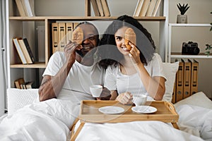 Multiethnic couple in love enjoying breakfast in bed