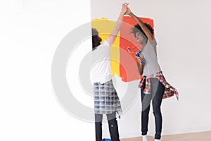 Multiethnic couple painting interior wall