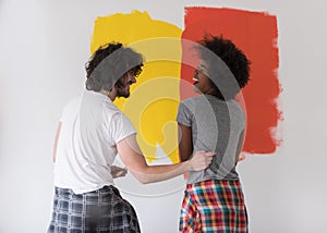 Multiethnic couple painting interior wall