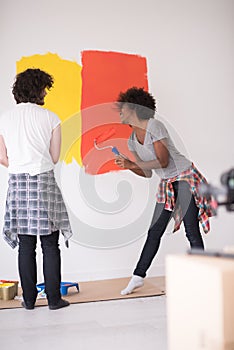 Multiethnic couple painting interior wall