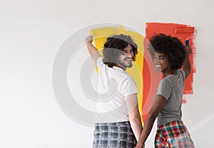 Multiethnic couple painting interior wall