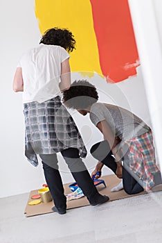 Multiethnic couple painting interior wall