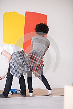 Multiethnic couple painting interior wall