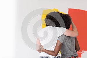 Multiethnic couple painting interior wall