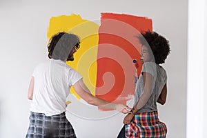 Multiethnic couple painting interior wall