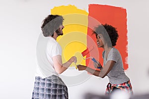 Multiethnic couple painting interior wall