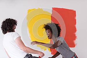 Multiethnic couple painting interior wall