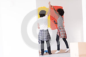 Multiethnic couple painting interior wall