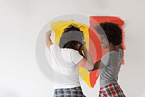 Multiethnic couple painting interior wall