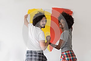 Multiethnic couple painting interior wall