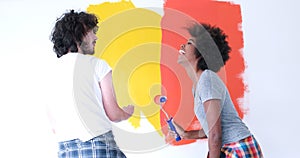 Multiethnic couple painting interior wall