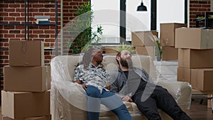 Multiethnic couple relaxing on sofa after unpacking furniture