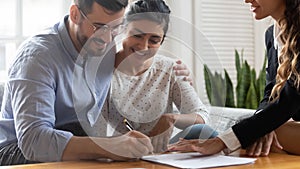 Multiethnic couple signing rental contract during meeting with realtor