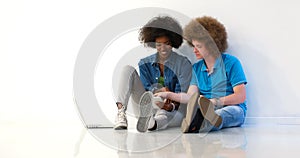 Multiethnic couple sitting on the floor using a laptop and table