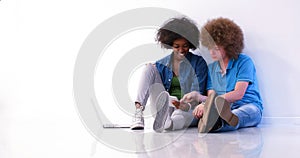 Multiethnic couple sitting on the floor using a laptop and table