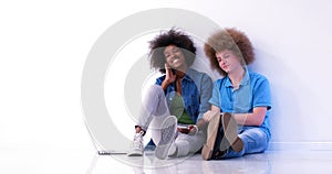 Multiethnic couple sitting on the floor using a laptop and table