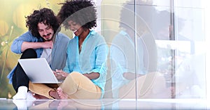 Multiethnic couple using a laptop on the floor