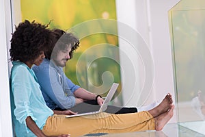 Multiethnic couple using a laptop on the floor