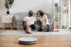 Multiethnic couple using remote control for vacuum cleaner