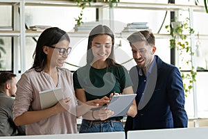 Multiethnic coworkers discuss ideas in office using tablet