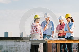 Multiethnic diverse group of engineers or business partners at construction site, working together on building`s blueprint