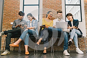Multiethnic diverse group of young and adult people using smartphone, laptop computer, digital tablet together