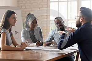 Multiethnic employees listen to boss talking at meeting