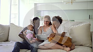 Multiethnic family with children using device and sitting on sofa at home room spbd.