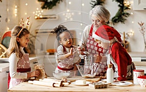 Multiethnic family, grandmother and three little kids, cooking Christmas cookies together in kitchen