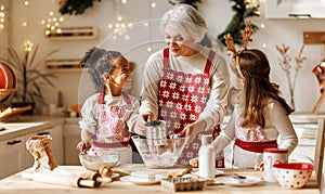 Multiethnic family, grandmother and two little kids, cooking Christmas cookies together in kitchen