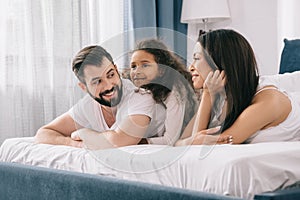 Multiethnic family with one child lying together in bed