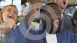 Multiethnic fans watching sport game in pub, cheering for favorite team victory