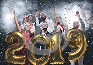 Multiethnic friends holding 2019 balloons at New Year party