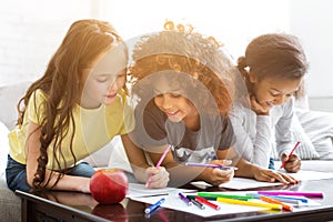 Multiethnic girls drawing at table with colorful pencils