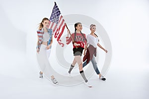 Multiethnic girls walking with american flag and celebrating 4th july