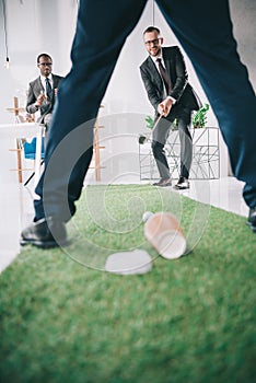 multiethnic group of businessmen playing mini golf