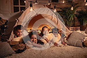 multiethnic group of children resting in handmade tent together