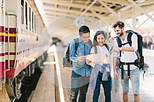 Multiethnic group of friends, backpack travelers, or college students using local map navigation together at train station
