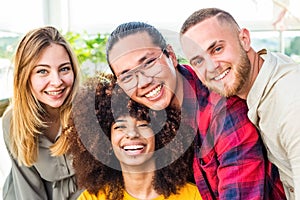 Multiethnic group of friends taking selfie indoor with a curly woman in foreground.two young women and two men in summer.people