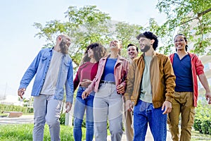 Multiethnic group of friends walking in the street outdoors laughing and having fun. diverse people celebrating life together