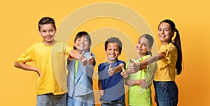 Multiethnic group of kids friends on yellow, showing thumb up